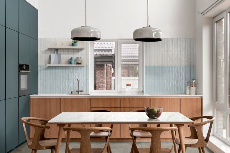 Küchenszene mit Esstisch, Stühlen, Küchenschränken und Pendelleuchten