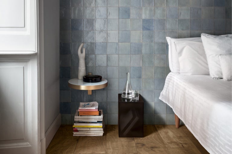 Schlafzimmer mit blauen Fliesen an der Wand, Nachttischen und Holzboden