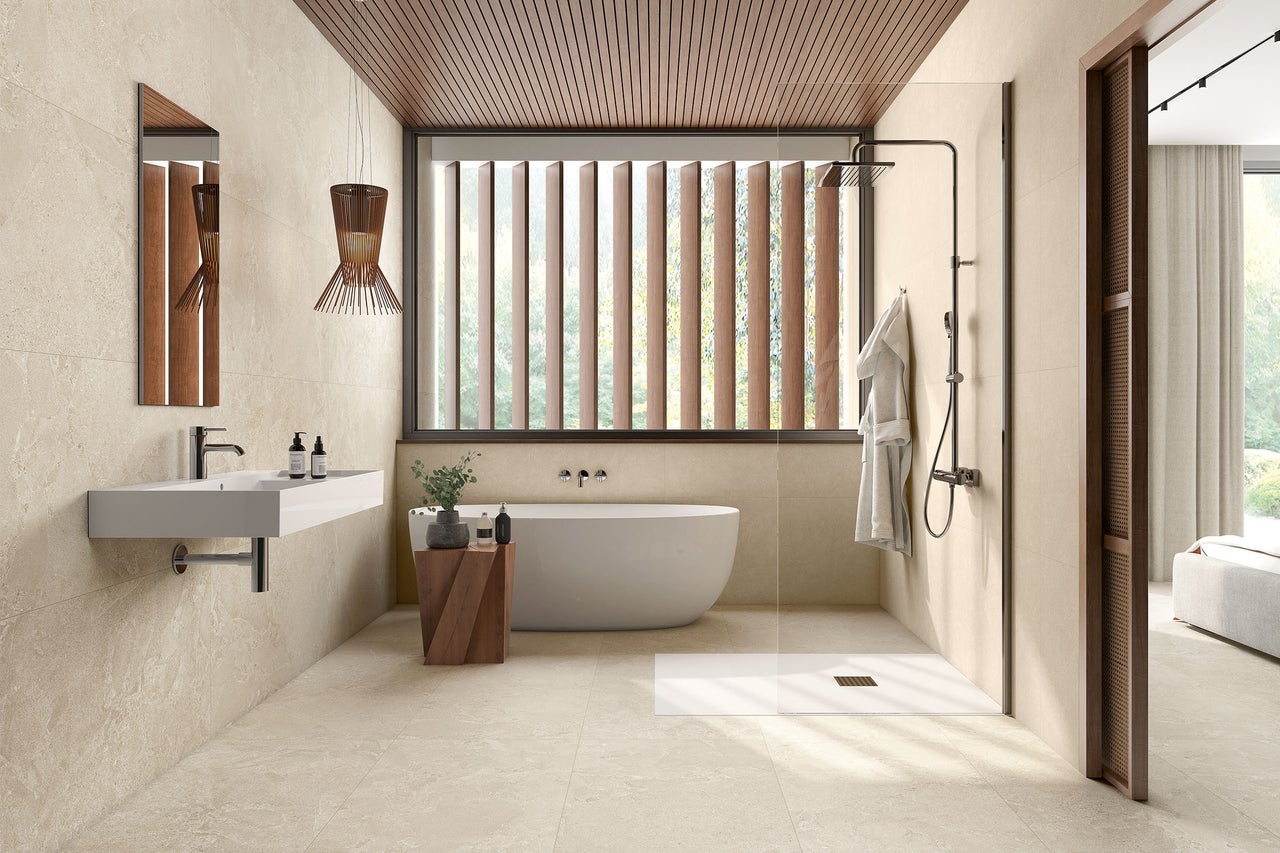 Modernes, helles Badezimmer mit Fliesen in Natursteinoptik, freistehender Badewanne, begehbarer Dusche und Holzlamellendecke.