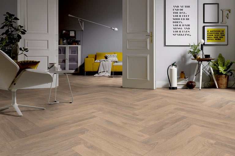 Heller Raum mit Fischgrätenparkett, Sessel und gelbem Sofa