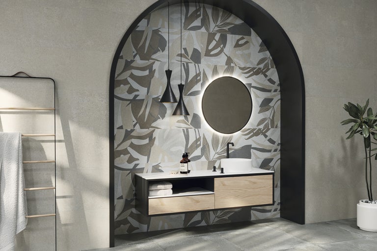 Modernes Badezimmer mit Blattmuster-Fliesen in einer Bogennische, hängendem Waschtisch aus Holz, rundem Spiegel mit Beleuchtung und Pendelleuchten.