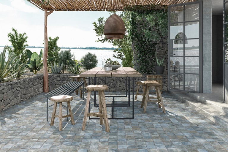 Terrassenszene mit Holztisch, Hockern und Sitzbank im Freien mit Seeblick