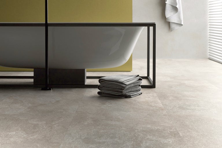 Badezimmer mit freistehender Badewanne, Handtüchern und Fliesenboden.