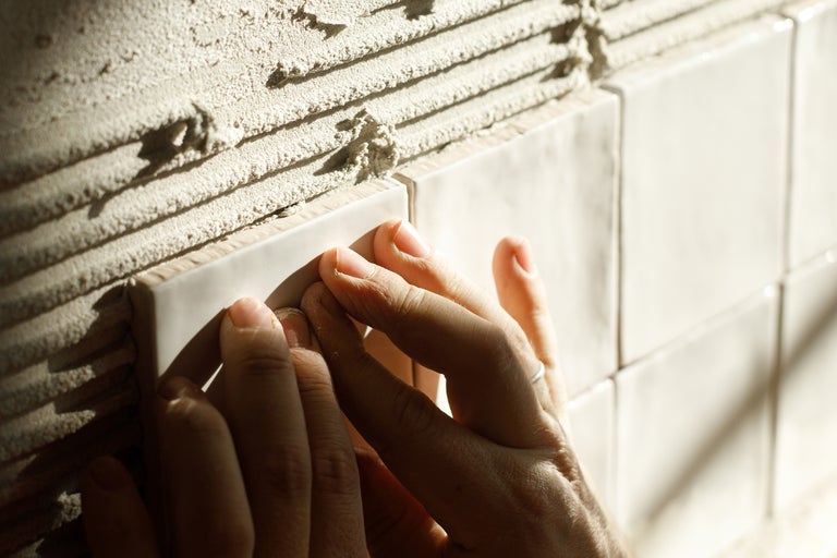 Hand beim Verlegen von Wandfliesen