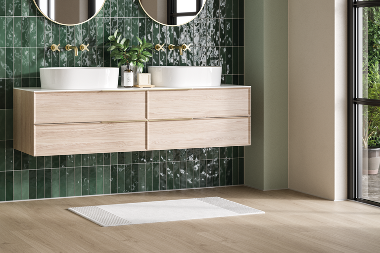 Helles Badezimmer mit Waschtischunterschrank, Aufsatzwaschbecken, Wandarmaturen und grünen Fliesen.