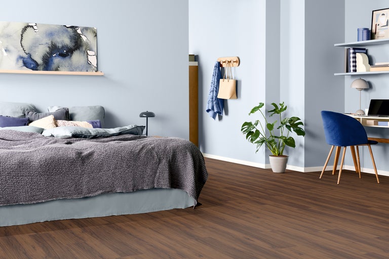 Schlafzimmer mit Bett, Schreibtisch und braunem Laminatboden