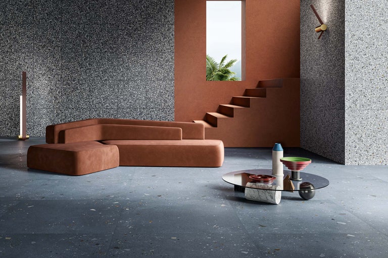 Helles Wohnzimmer mit Terrazzoboden, braunem Sofa und Treppe