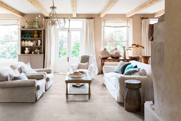 Wohnzimmer mit Fliesenboden, Sofa, Sessel, Couchtisch und Dekoration