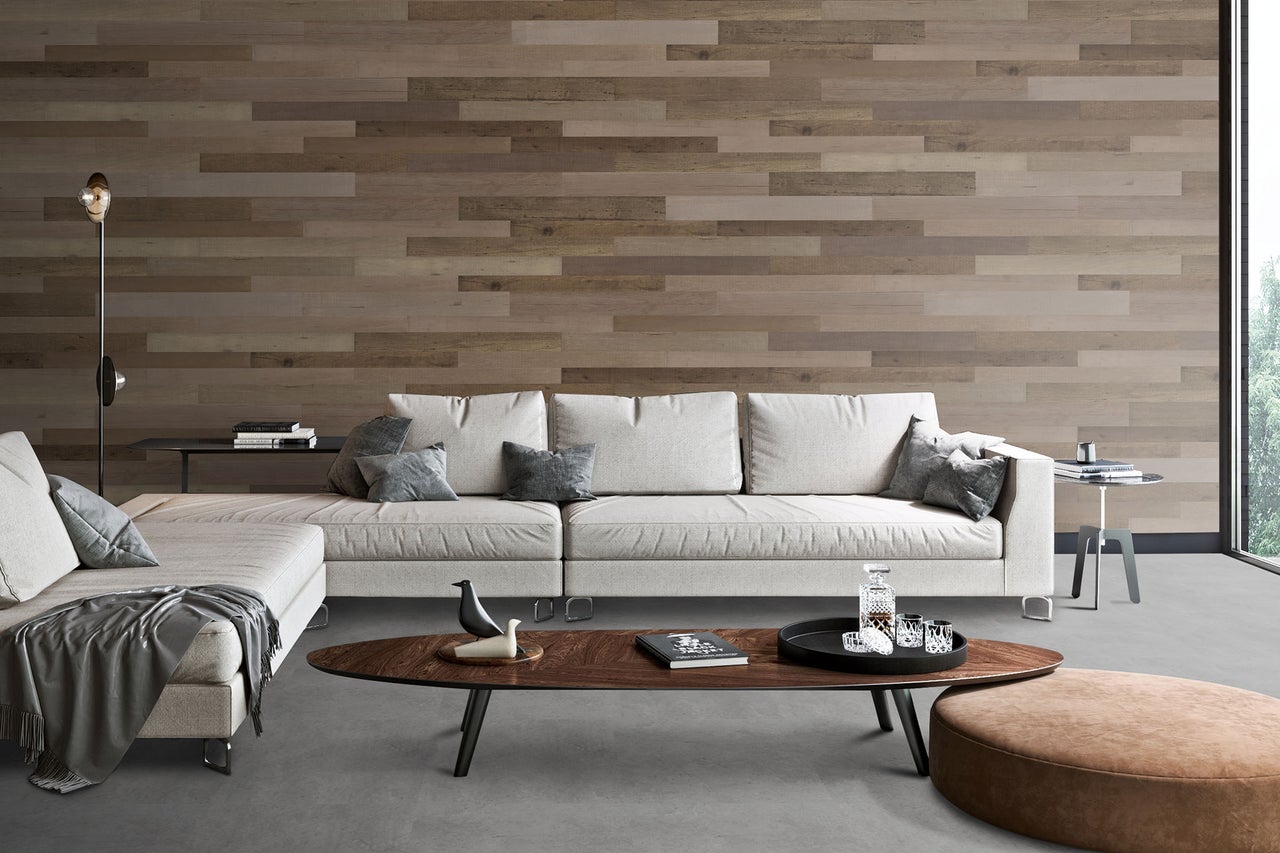 Modernes Wohnzimmer mit Wand aus horizontalen Holzpaneelen, hellem Ecksofa und dunklem Holz-Couchtisch auf grauem Boden.