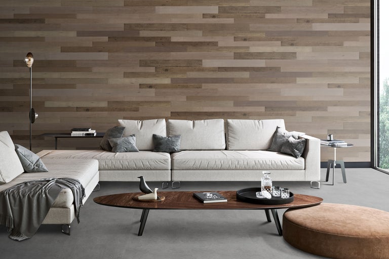 Modernes Wohnzimmer mit Wand aus horizontalen Holzpaneelen, hellem Ecksofa und dunklem Holz-Couchtisch auf grauem Boden.