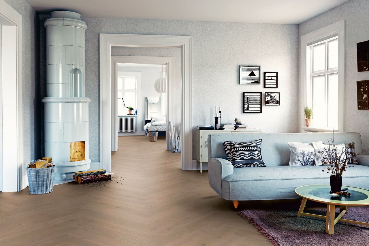 Heller Wohnraum mit Fischgrätenparkett, Kaminofen und Sofa