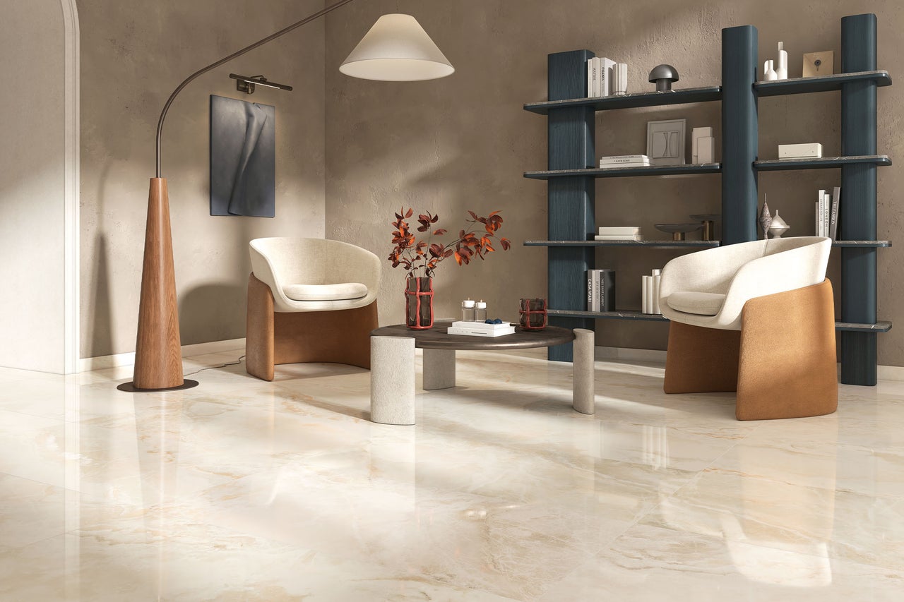 Wohnzimmer mit polierten Fliesen in Marmoroptik, zwei Sesseln, Couchtisch und einem hohen Regal in einem modernen, eleganten Einrichtungsstil.