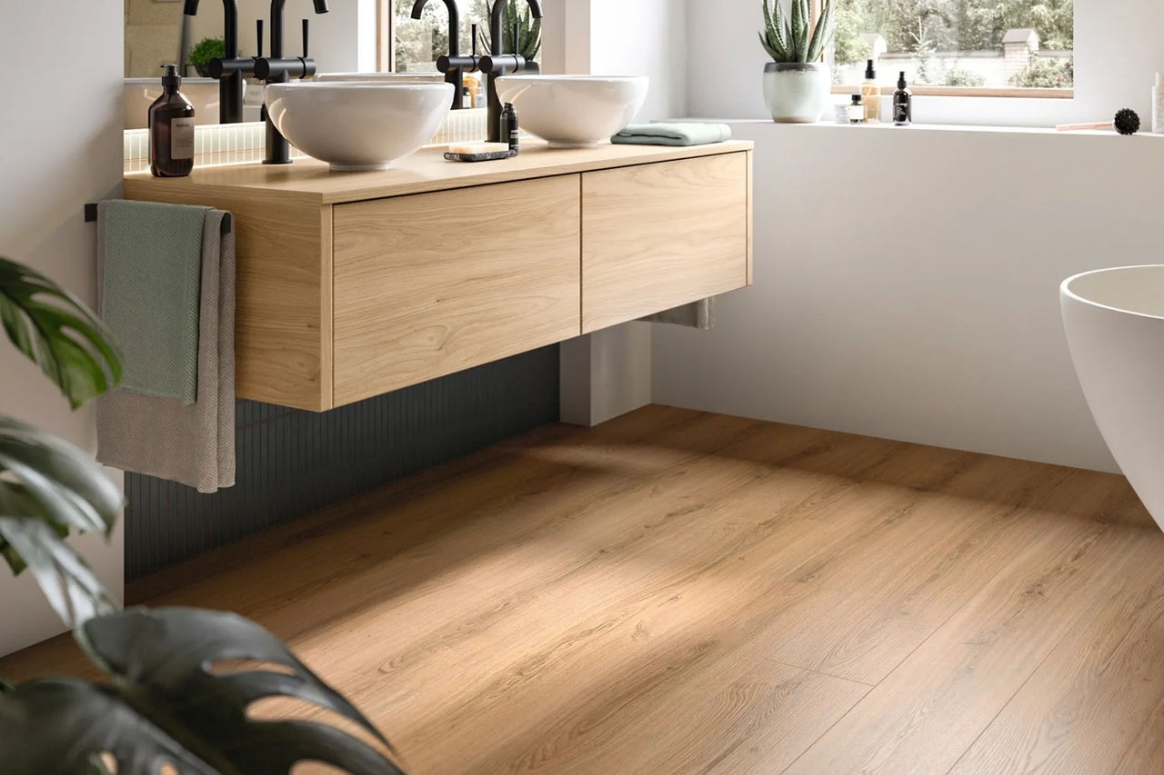 Modernes Badezimmer mit hängendem Waschtischunterschrank in Holzoptik, zwei weißen Aufsatzwaschbecken, schwarzen Armaturen und Laminatboden.