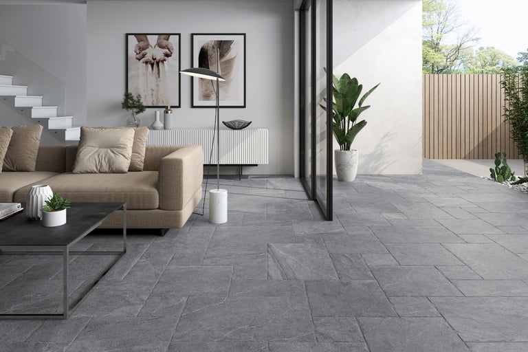 Modernes Wohnzimmer und Terrasse mit Bodenfliesen in Steinoptik aus Feinsteinzeug für einen nahtlosen Übergang von innen nach außen.