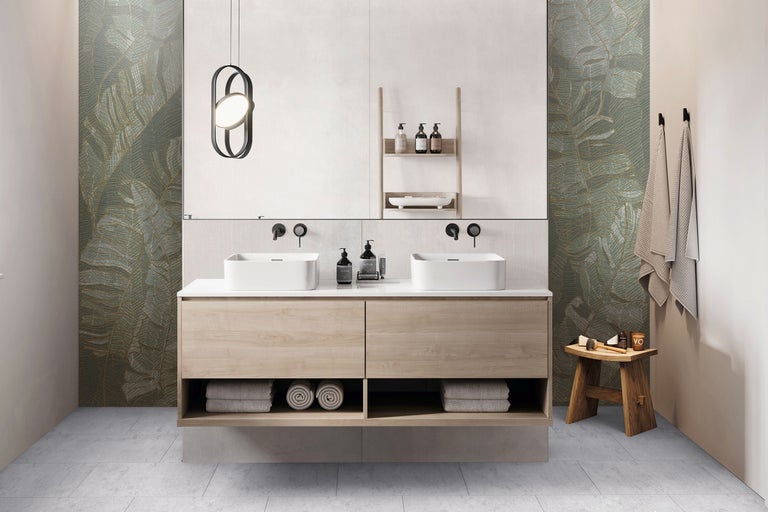 Badezimmer mit Doppelwaschtisch, Waschtischunterschrank aus Holz, Handtüchern, Hocker und Wandtapete mit Blättermuster