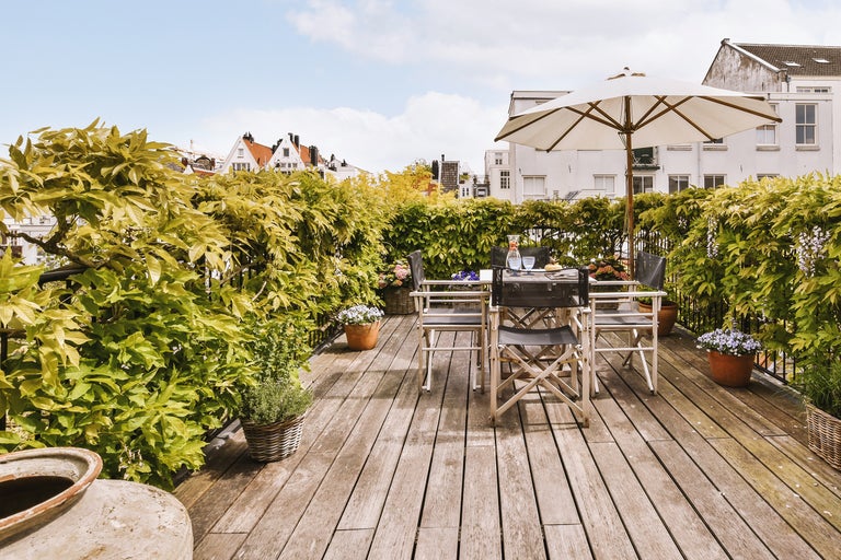 Terrasse mit Holzdeck, Tisch, Stühlen, Sonnenschirm und Pflanzen