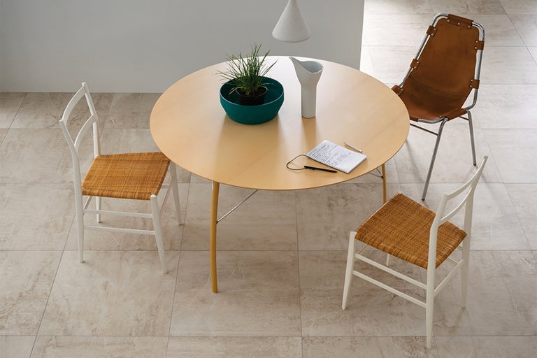 Szene mit rundem Holztisch, Stühlen, Topfpflanze, Notizblock und Krug