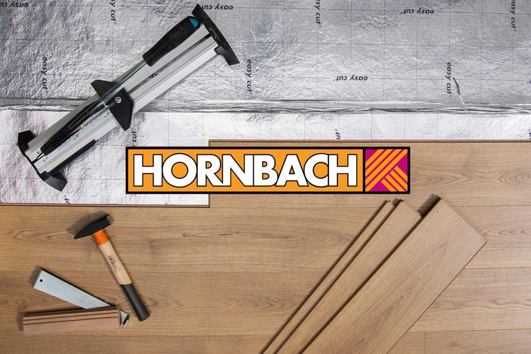 Szene mit Laminatschneider, Trittschalldämmung, Hammer und Laminatdielen auf Holzboden